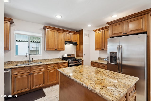 2726 E Fairmount Ave, Phoenix, AZ 85016 - kitchen with brown cabinets, a sink, light stone counters, under cabinet range hood, and stainless steel appliances
