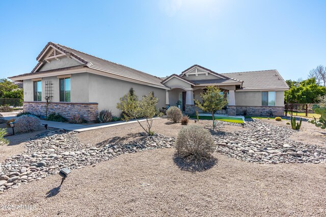 view of front of property featuring stone siding, fence, and stucco siding