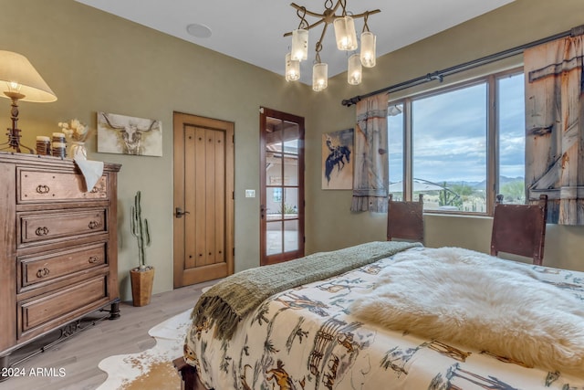 bedroom with light wood-type flooring and an inviting chandelier