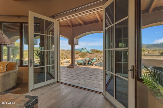 doorway to outside with a healthy amount of sunlight, hardwood / wood-style flooring, vaulted ceiling with beams, and french doors