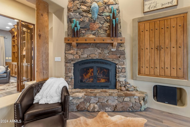 living room featuring wood-type flooring and a stone fireplace