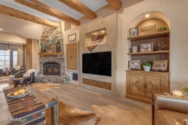 living room featuring beamed ceiling, wood-type flooring, and a fireplace