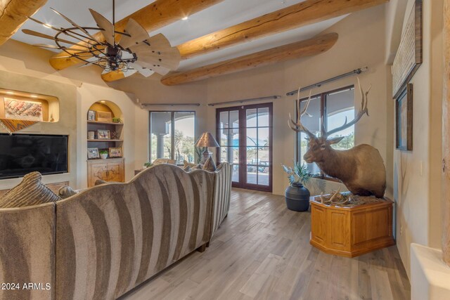 living room featuring french doors, beam ceiling, built in shelves, hardwood / wood-style flooring, and ceiling fan