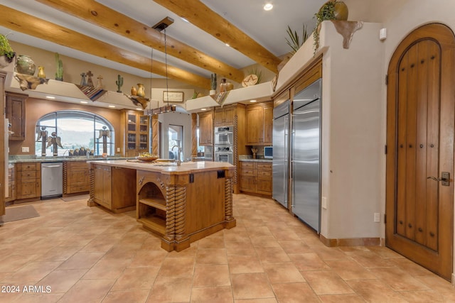 kitchen with a kitchen bar, appliances with stainless steel finishes, sink, a kitchen island, and beam ceiling