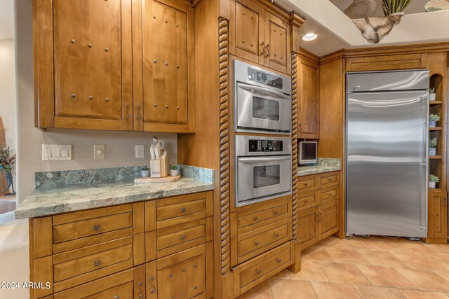 kitchen with light tile patterned floors, stainless steel appliances, and light stone countertops