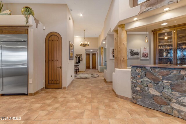 kitchen featuring decorative light fixtures, stainless steel built in fridge, a chandelier, and a towering ceiling