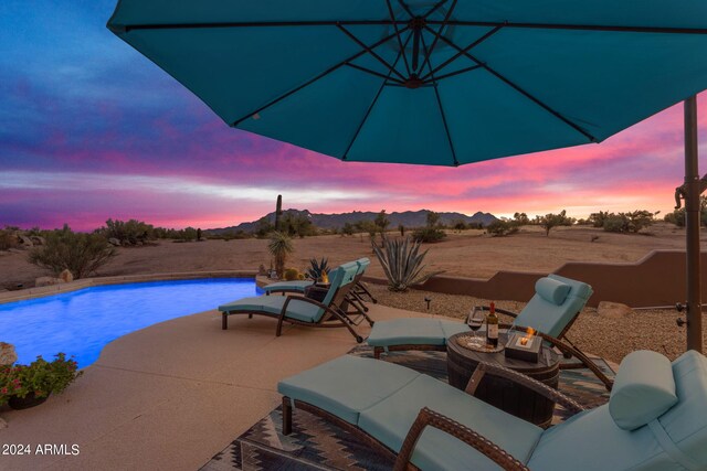 pool at dusk featuring an outdoor living space and a patio