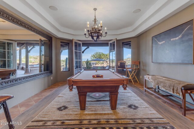 game room featuring an inviting chandelier, pool table, hardwood / wood-style floors, and a tray ceiling