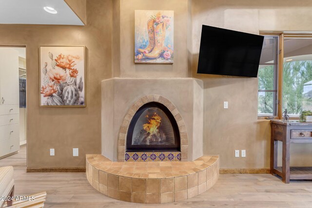 living room featuring a tiled fireplace and light hardwood / wood-style floors