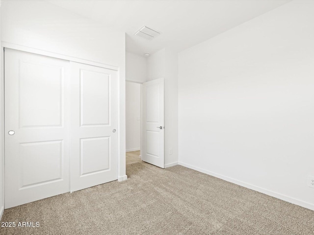 unfurnished bedroom featuring visible vents, baseboards, light colored carpet, and a closet