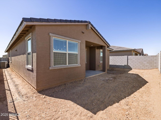 back of house with a tiled roof, stucco siding, central AC, and fence