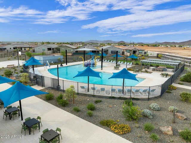 community pool featuring a patio area, a mountain view, fence, and a residential view