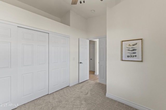 unfurnished bedroom with ceiling fan, a closet, and light carpet