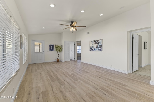 unfurnished living room featuring a wealth of natural light, ceiling fan, vaulted ceiling, and light wood-type flooring