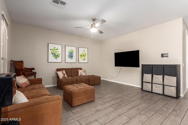 living room with a ceiling fan, light wood-type flooring, visible vents, and baseboards