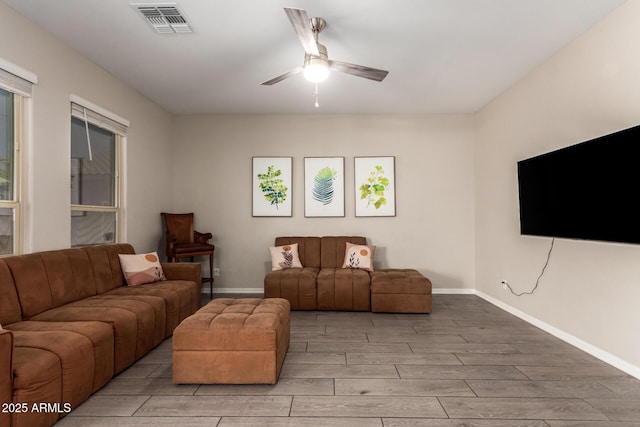 living area with baseboards, light wood finished floors, visible vents, and a ceiling fan