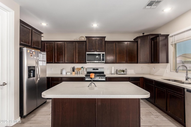 kitchen with stainless steel appliances, visible vents, decorative backsplash, a sink, and dark brown cabinets