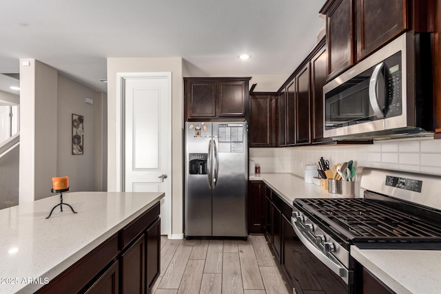 kitchen with light wood-style flooring, appliances with stainless steel finishes, decorative backsplash, and dark brown cabinets