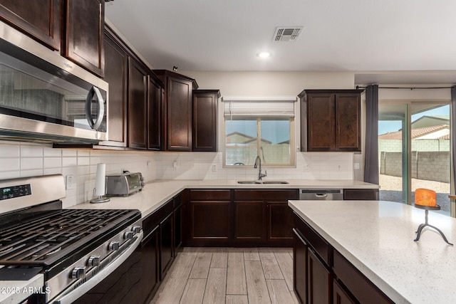 kitchen featuring light wood finished floors, appliances with stainless steel finishes, a sink, and a wealth of natural light