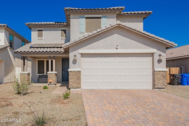 mediterranean / spanish-style house with covered porch, decorative driveway, stone siding, and solar panels