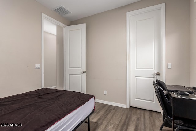 bedroom with visible vents, baseboards, and wood finished floors