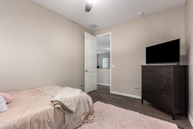 bedroom featuring ceiling fan, wood finished floors, visible vents, and baseboards