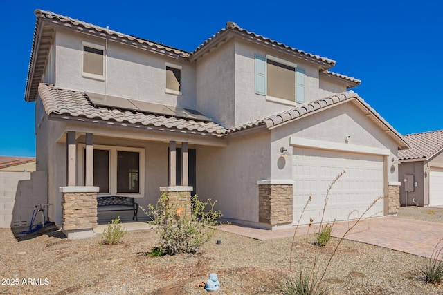 mediterranean / spanish house with roof mounted solar panels, a porch, decorative driveway, and stucco siding