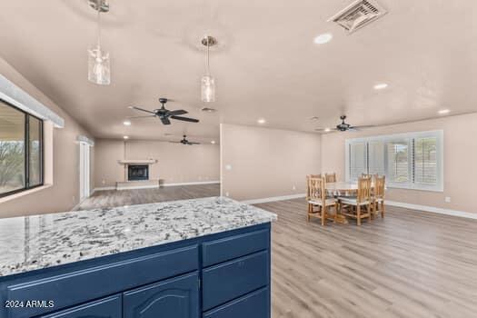 kitchen featuring light wood-type flooring, blue cabinetry, ceiling fan, and plenty of natural light