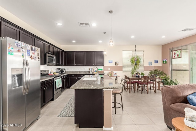 kitchen with light tile patterned floors, visible vents, a sink, appliances with stainless steel finishes, and a kitchen bar