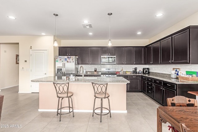 kitchen featuring light stone counters, visible vents, backsplash, and stainless steel appliances