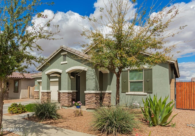 view of front facade featuring a tiled roof, stone siding, driveway, and stucco siding