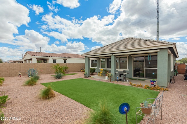 back of house with stucco siding, a lawn, a fenced backyard, and a patio area