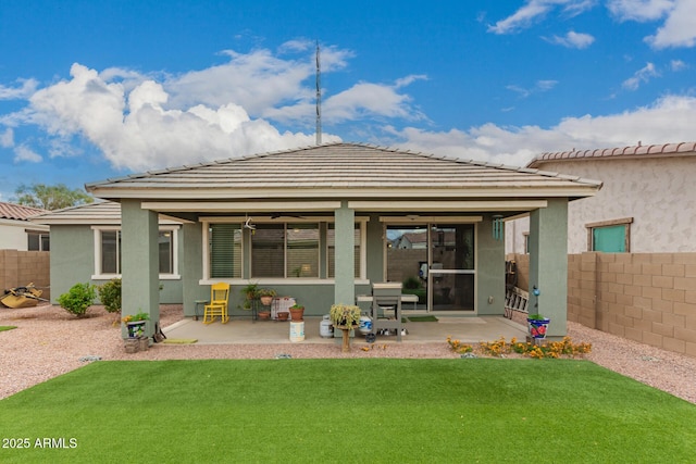 rear view of property featuring stucco siding, a patio area, a yard, and fence