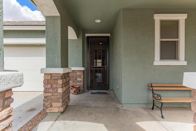 view of exterior entry with stucco siding, stone siding, and a garage