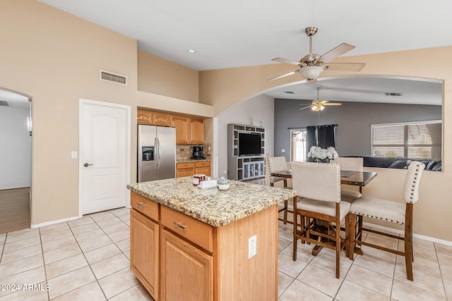 kitchen with stainless steel fridge with ice dispenser, light tile patterned floors, and a center island