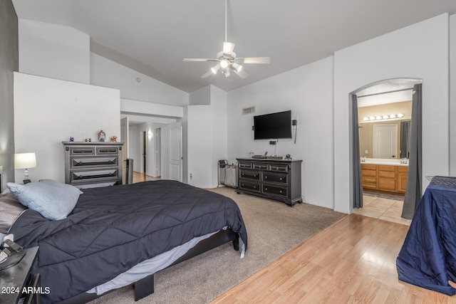 bedroom featuring light hardwood / wood-style floors, lofted ceiling, ceiling fan, and ensuite bath