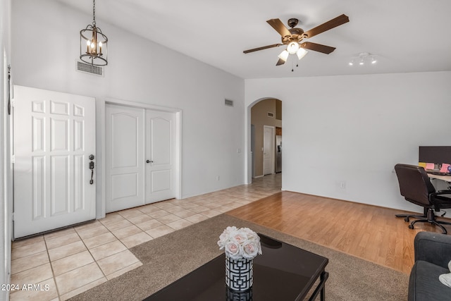 entryway featuring light tile patterned flooring, ceiling fan with notable chandelier, and vaulted ceiling