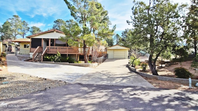 view of front of house featuring an outbuilding, a detached garage, fence, stairs, and concrete driveway