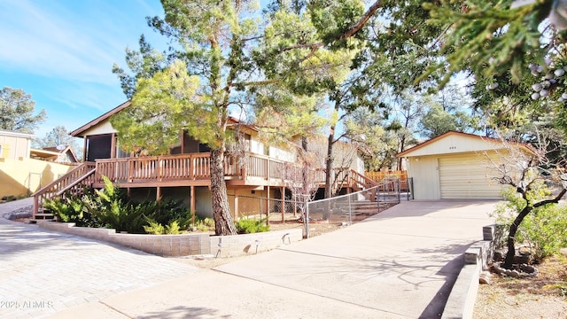 view of front of house with stairs, concrete driveway, an outdoor structure, and fence