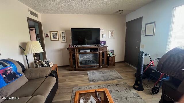 living room featuring visible vents, wood finished floors, and a textured ceiling