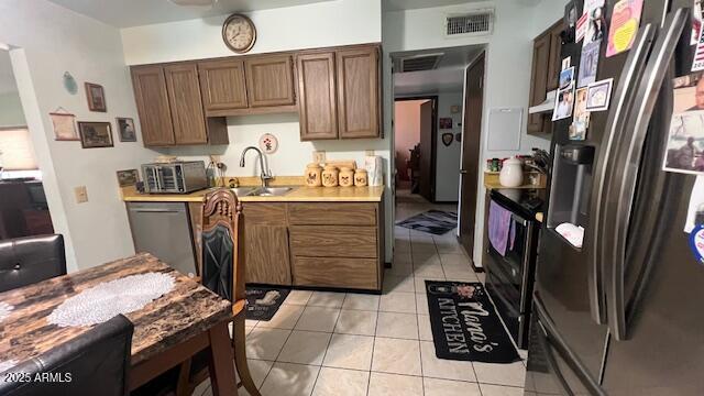 kitchen featuring light countertops, light tile patterned flooring, visible vents, stainless steel appliances, and a sink