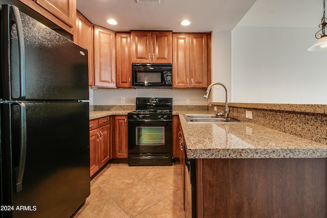 kitchen featuring light stone counters, sink, black appliances, light tile patterned floors, and hanging light fixtures