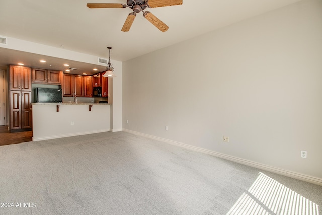 unfurnished living room with light colored carpet and ceiling fan