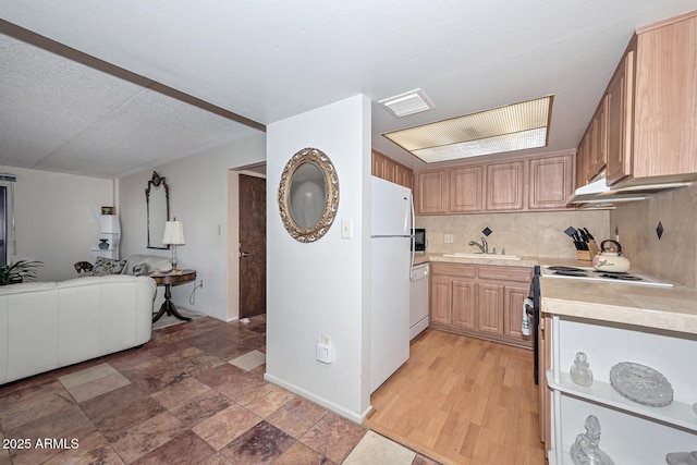 kitchen featuring sink, white appliances, hardwood / wood-style floors, tasteful backsplash, and a textured ceiling