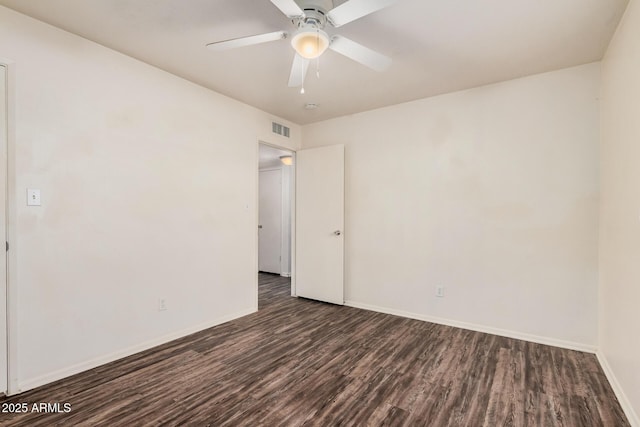 empty room featuring ceiling fan, dark wood finished floors, visible vents, and baseboards