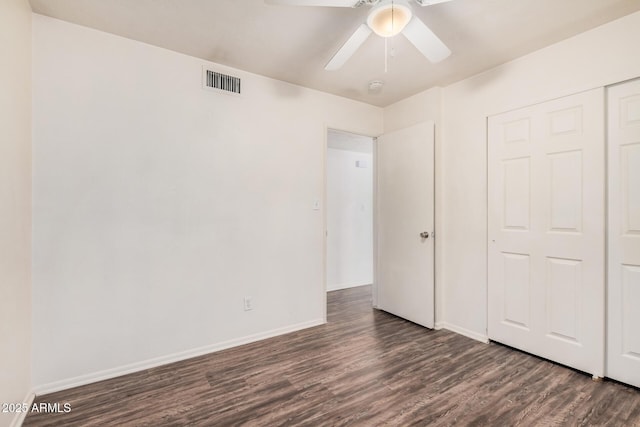 unfurnished bedroom featuring ceiling fan, visible vents, baseboards, a closet, and dark wood finished floors