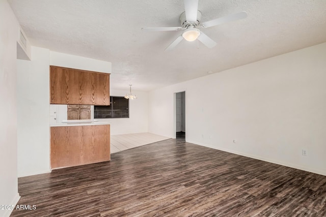 unfurnished living room featuring a textured ceiling, visible vents, dark wood-style flooring, and ceiling fan with notable chandelier