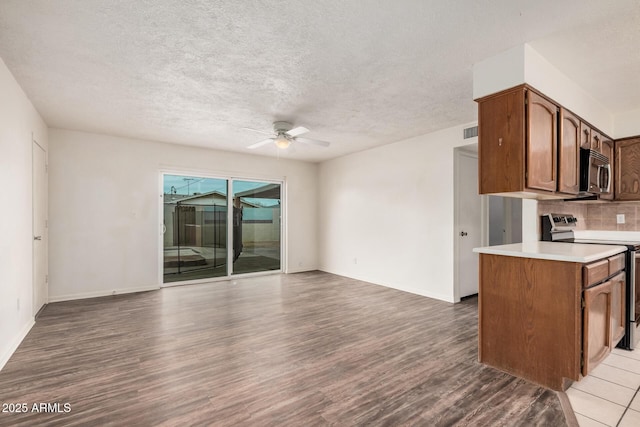 kitchen with light wood finished floors, stainless steel appliances, light countertops, open floor plan, and ceiling fan