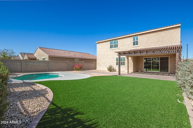 rear view of property featuring a lawn, a patio area, and a fenced in pool