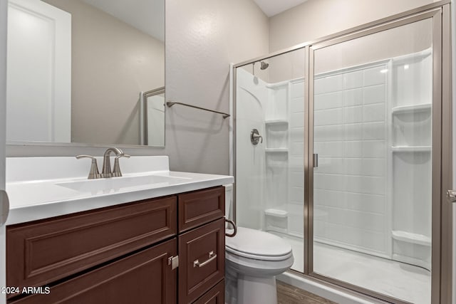 bathroom with a shower with door, vanity, hardwood / wood-style floors, and toilet